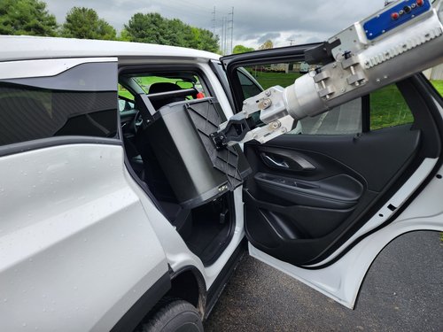 A black Argus case x-rays into a car while mounted on a large robot